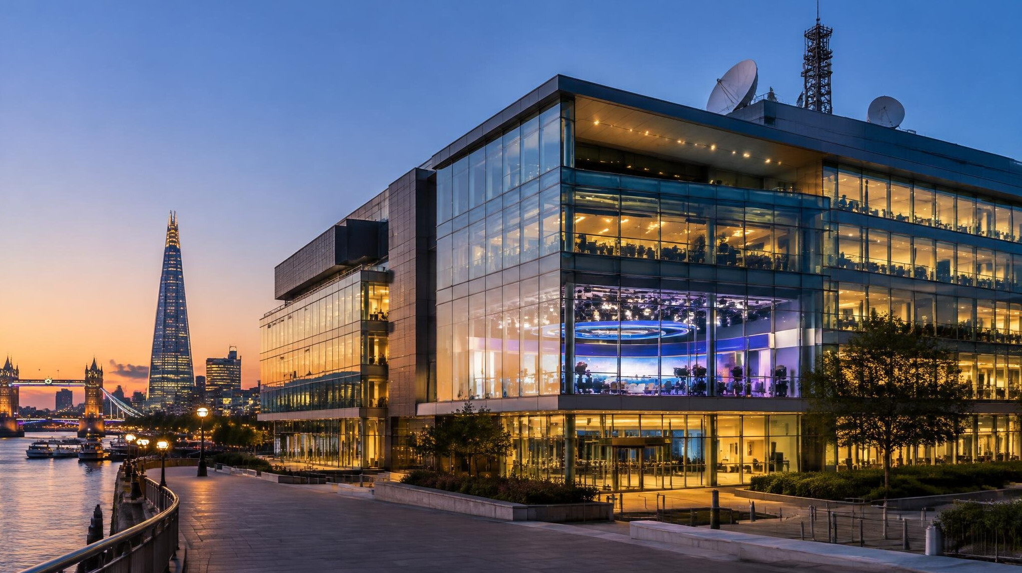 Modern broadcast centre building at dusk with lit windows